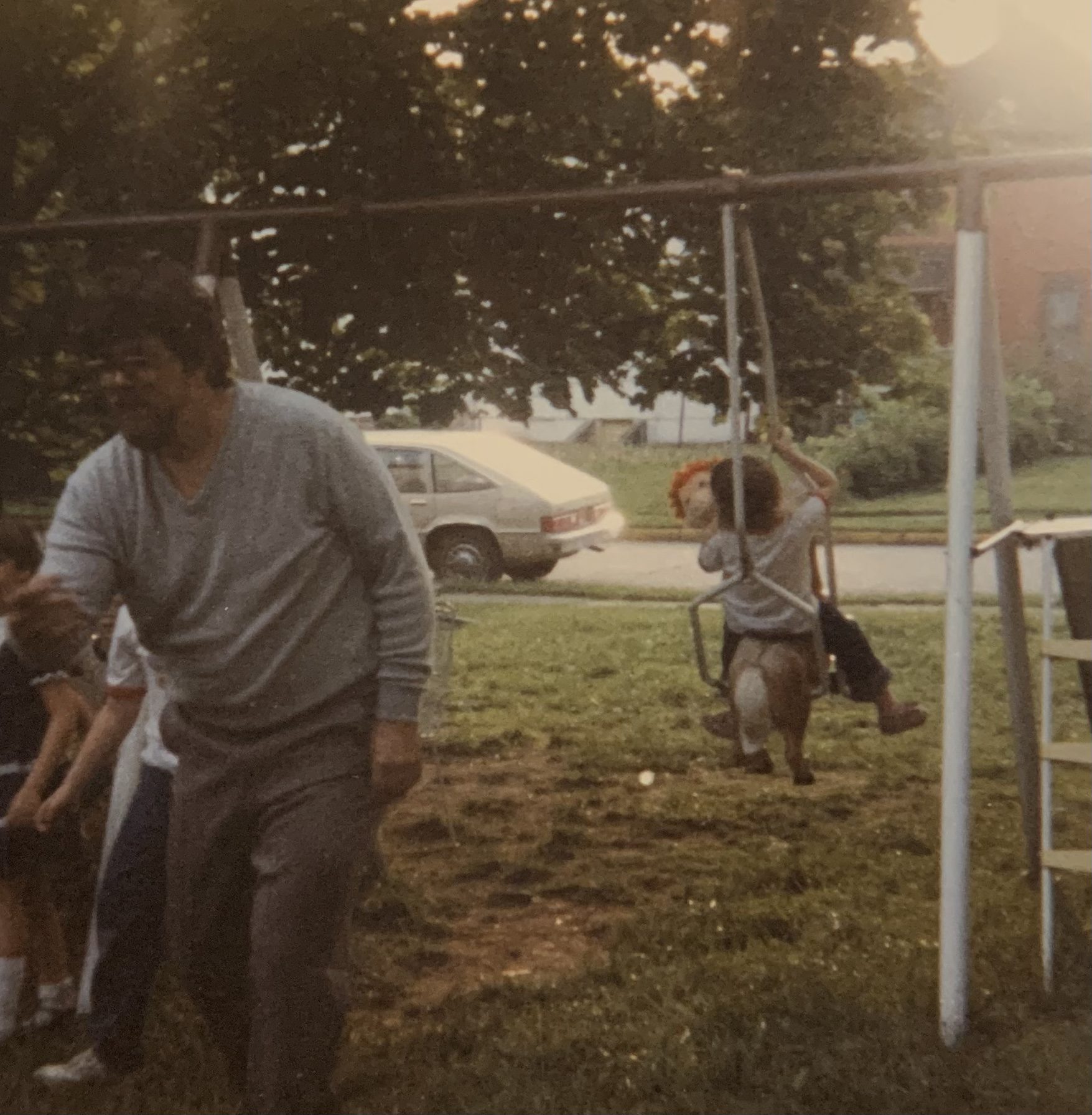 My dad playing a game at a birthday party, behind my swing set.